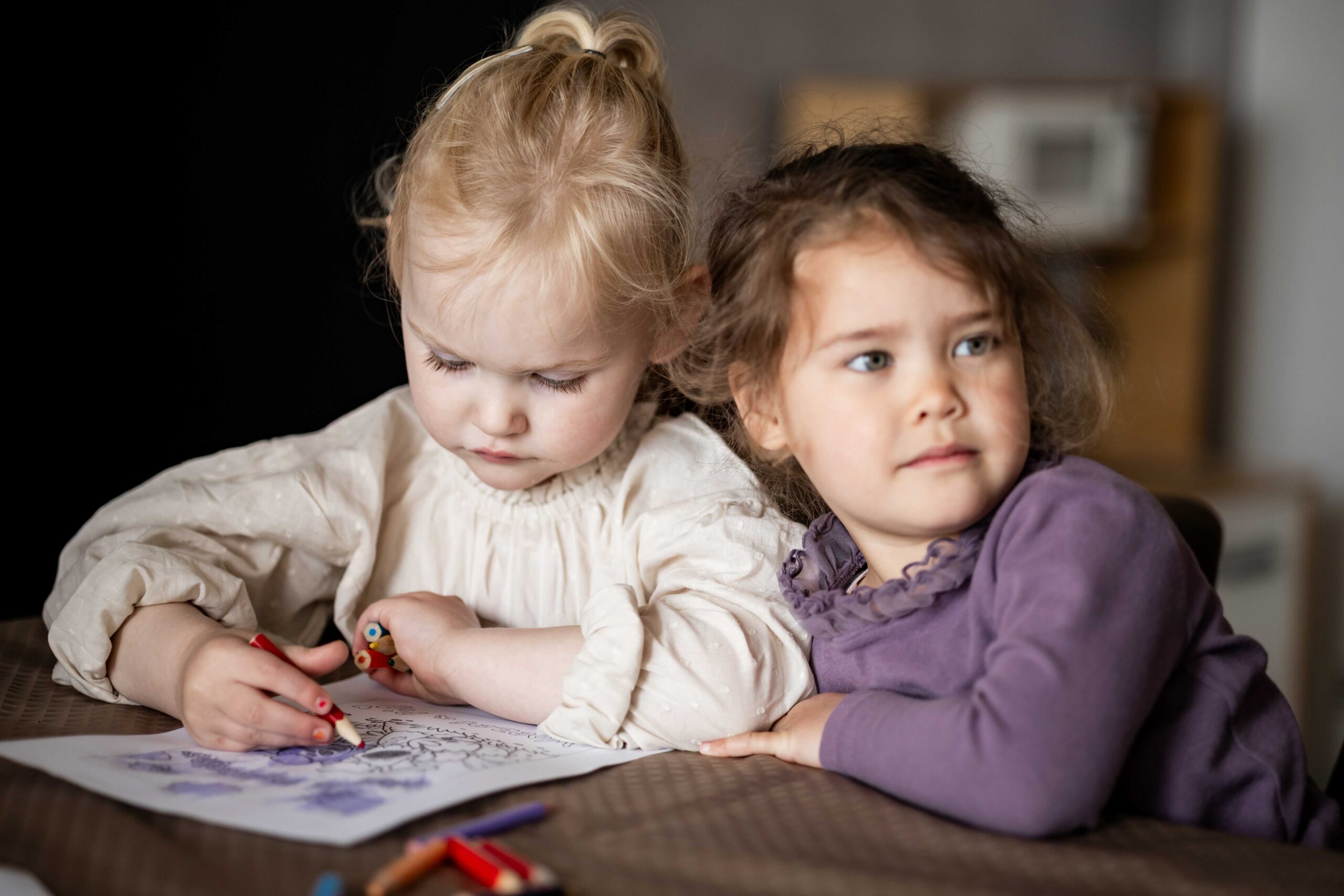 Twee meisjes tekenen samen aan tafel tijdens de kidsgroep