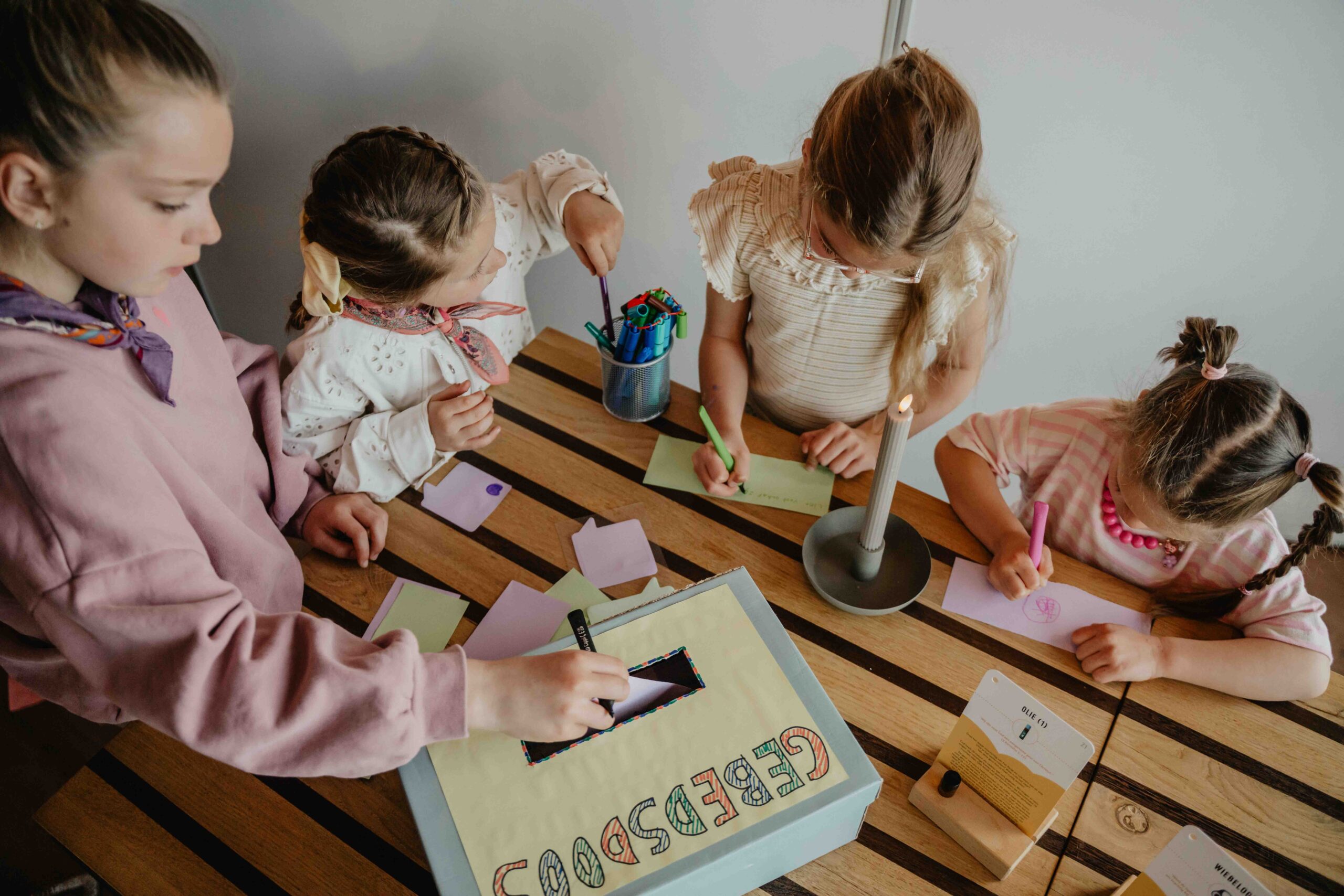 Vier meisjes knutselen aan tafel met de gebedsdoos van Mozaiek Kids