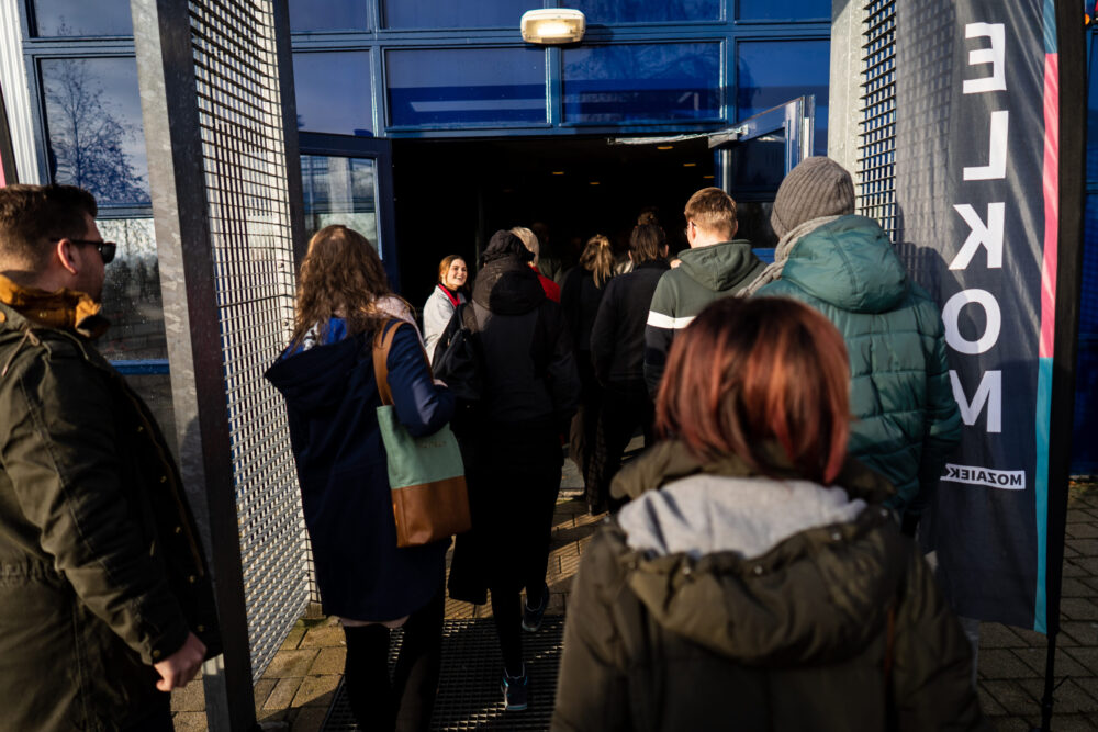 Bezoekers lopen door de ingang naar binnen bij Mozaiek033