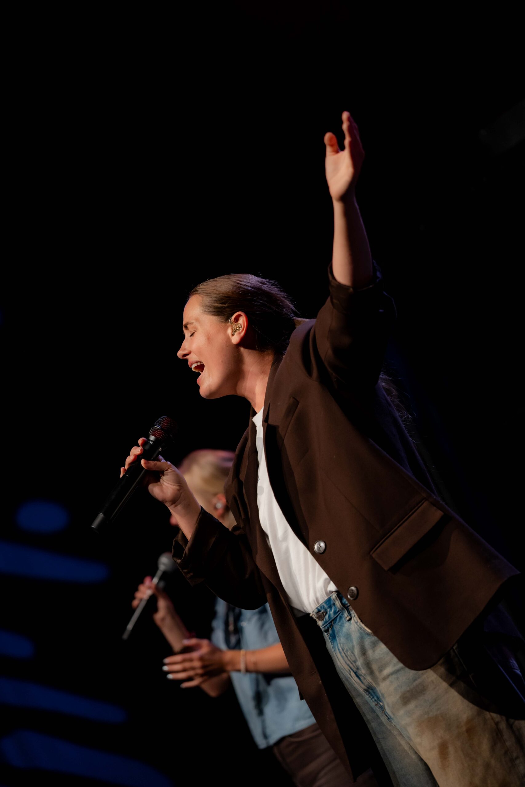 Zangeres zingt met haar arm omhoog tijdens de worship