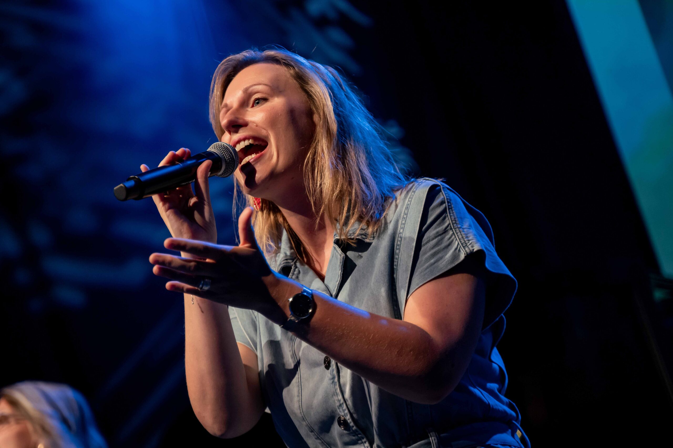 Zangeres zingt met microfoon in blauw podiumlicht