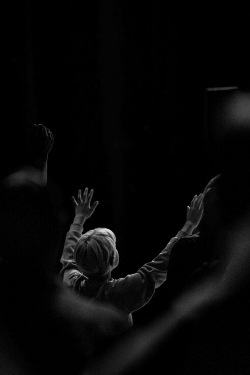 Bezoekers in de zaal heffen hun handen op tijdens de worship