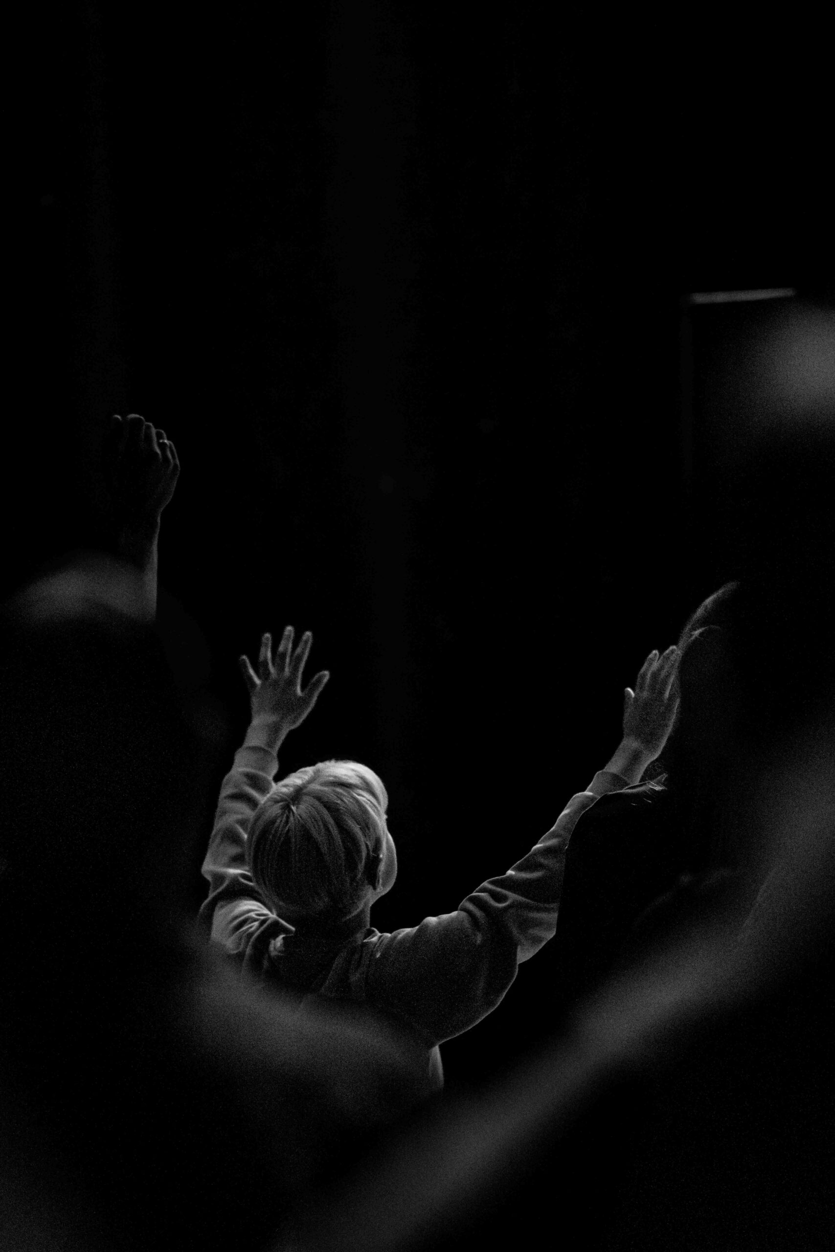 Bezoekers in de zaal heffen hun handen op tijdens de worship