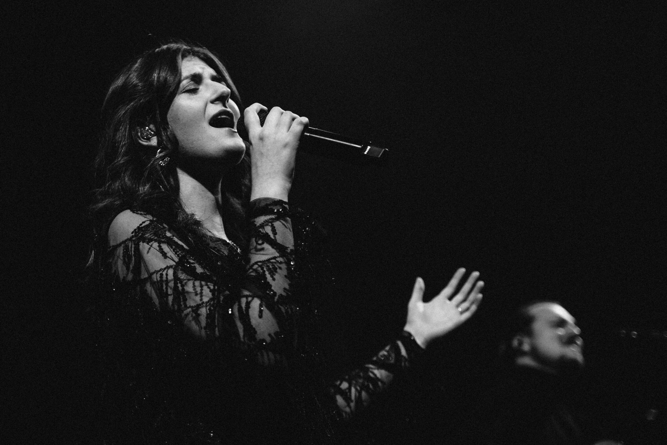 Zangeres zingt met microfoon tijdens de worship, in zwart-wit