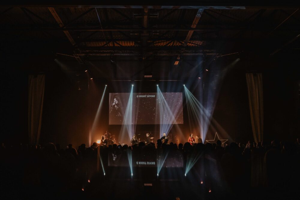 Overzicht van de zaal met het podium en de lichtshow tijdens een dienst
