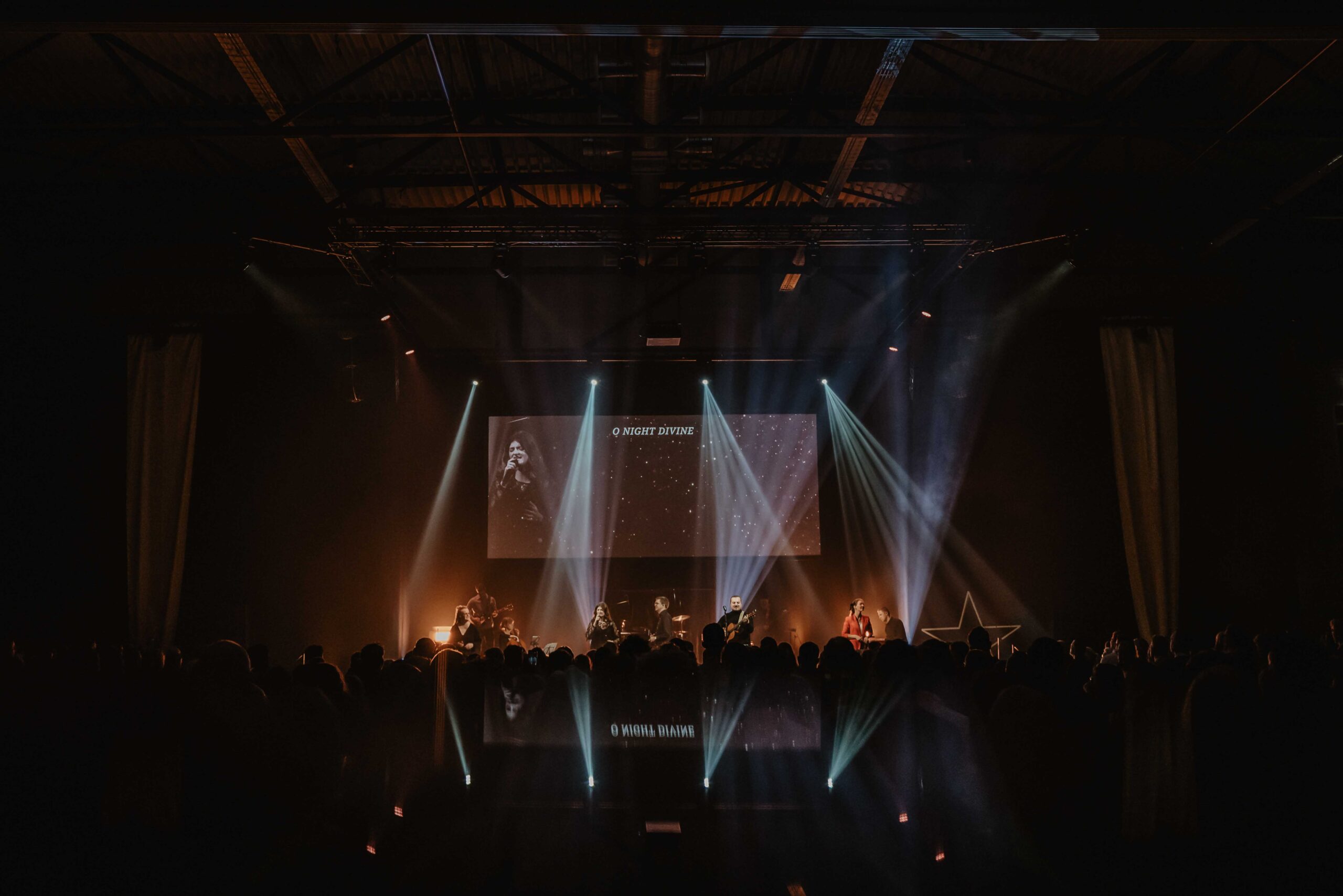Overzicht van de zaal met het podium en de lichtshow tijdens een dienst
