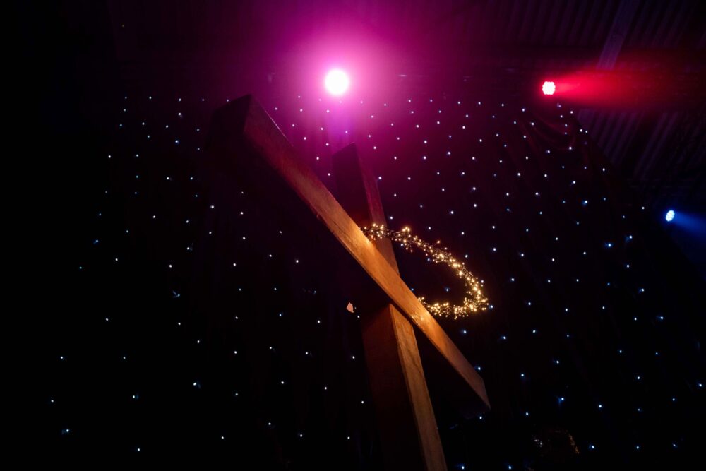 Houten kruis met lichtjes tegen een donkere achtergrond