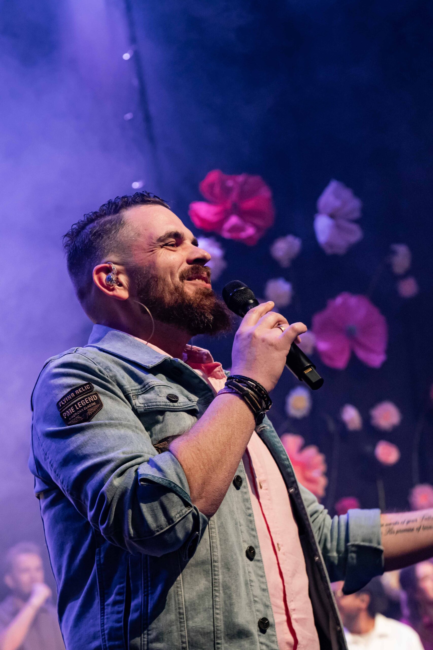 Worshipleider zingt met microfoon in paars licht
